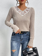 Person wearing a ribbed sweater with lace details and jeans against a white background
