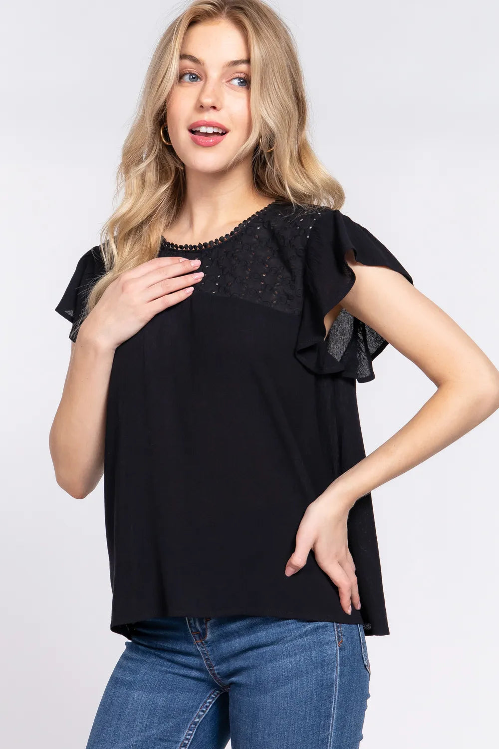 Woman wearing a black top with lace details on a white background