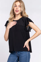 Woman wearing a black top with lace details on a white background