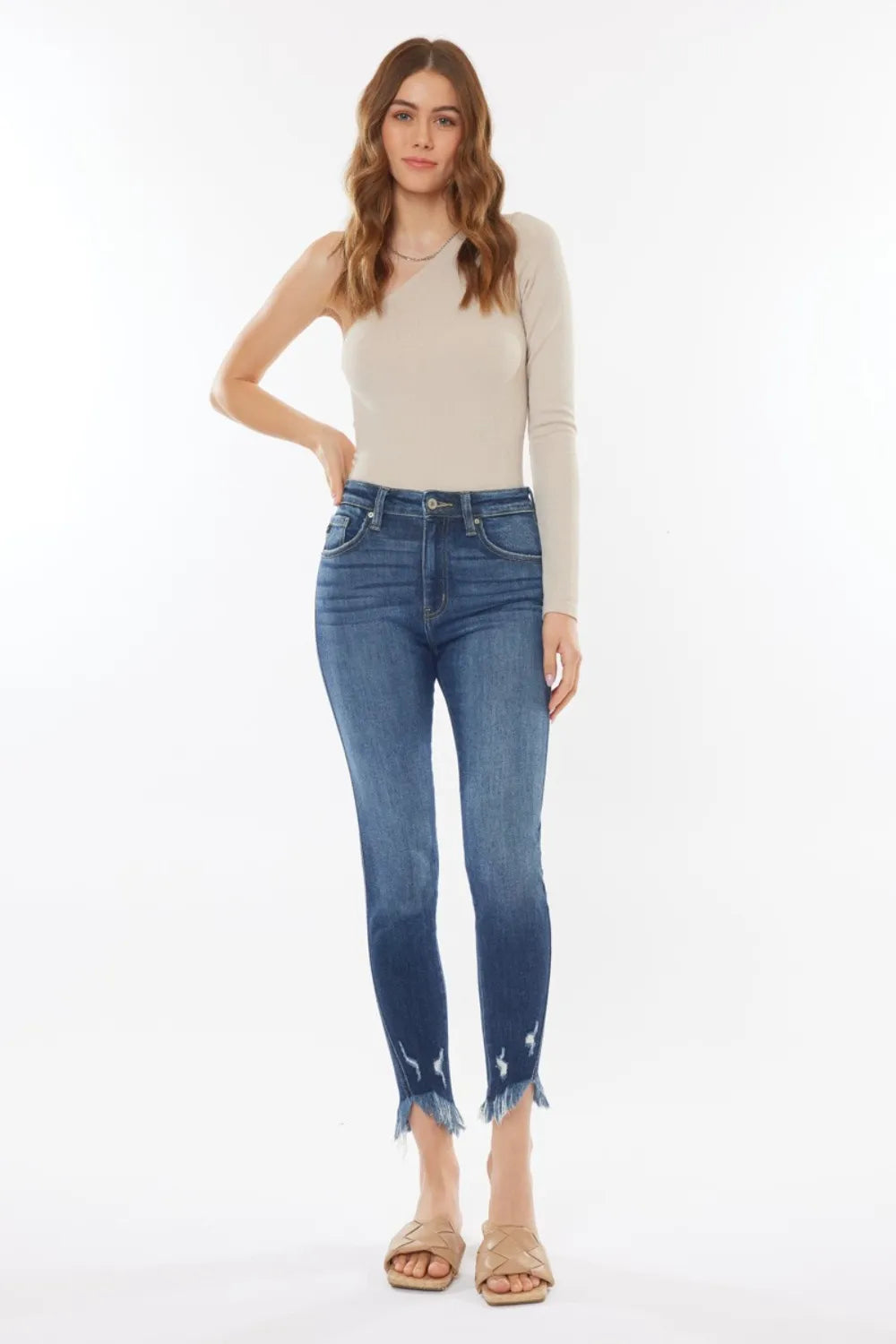 Woman wearing a beige top and blue jeans on a white background