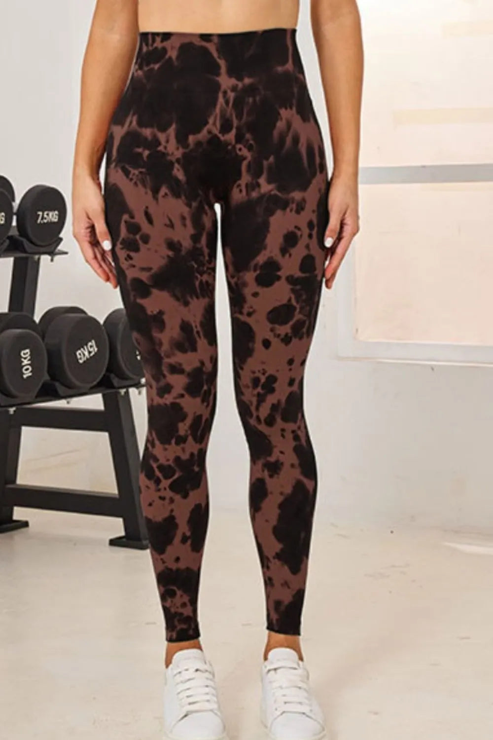 Person wearing brown and black tie-dye leggings in a gym setting