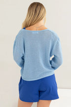 Woman wearing a light blue sweater and blue shorts against a white background