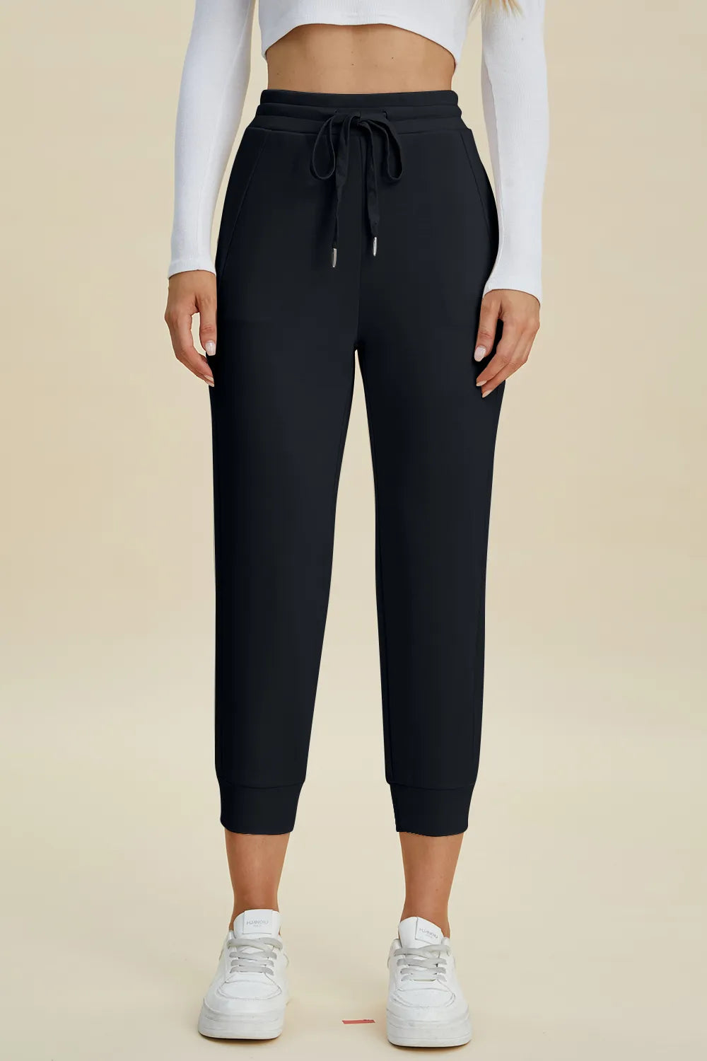 Person wearing black jogger pants with a beige background