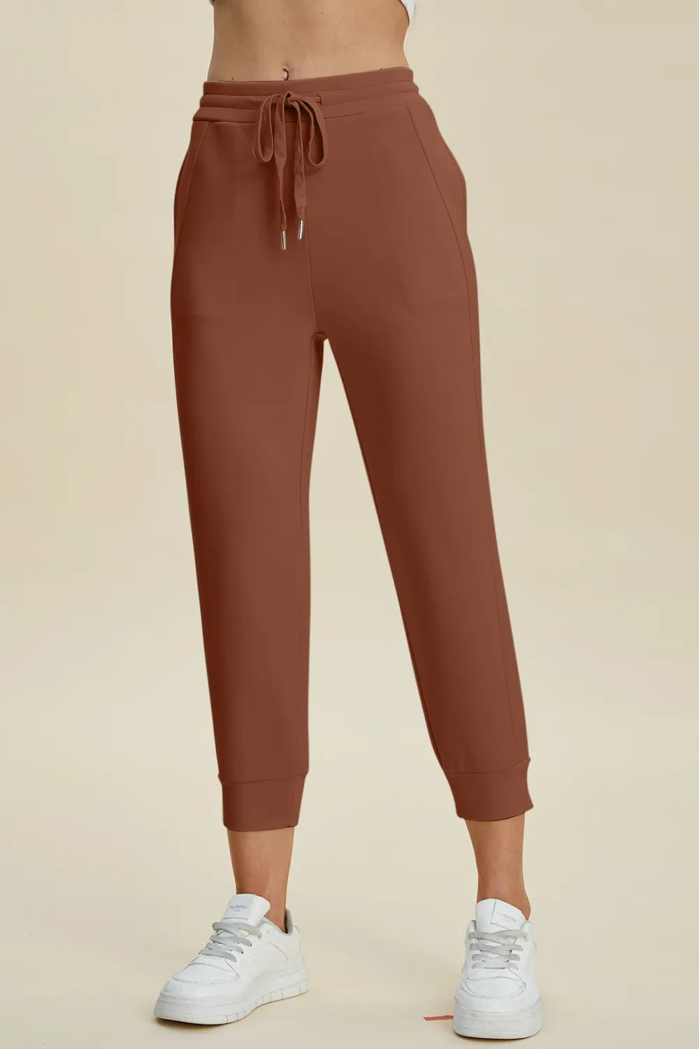 Brown sweatpants worn by a person on a beige background