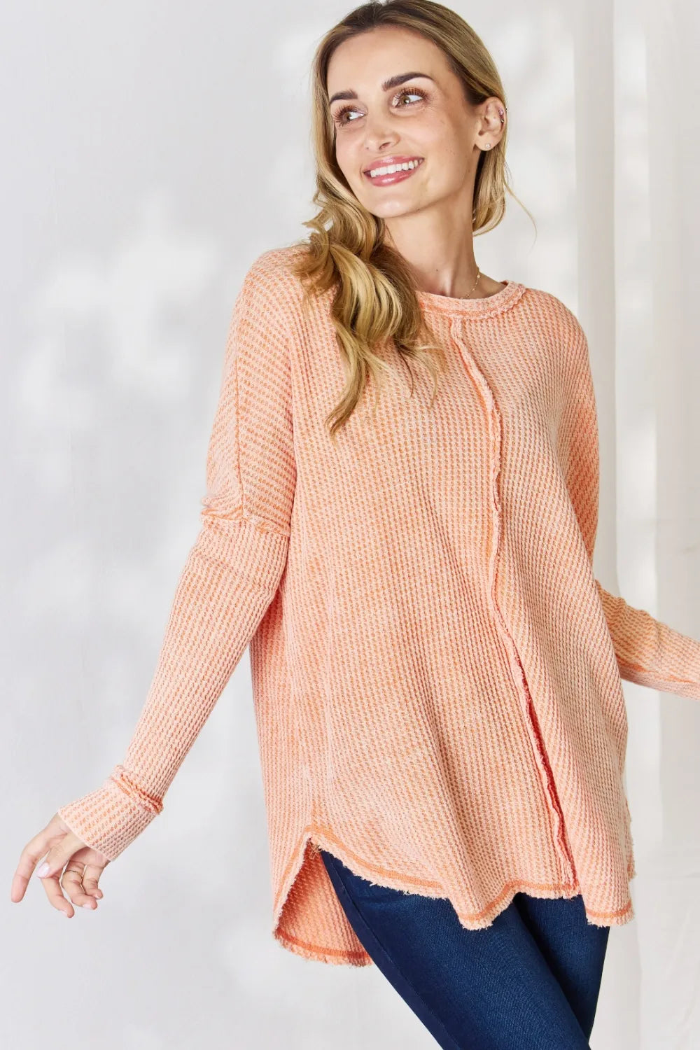 Woman wearing a peach-colored sweater against a white background