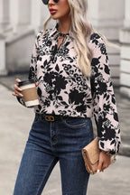 Woman wearing a floral blouse and jeans, holding a coffee cup and clutch.