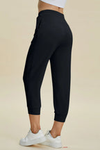 Black jogger pants worn by a person on a beige background