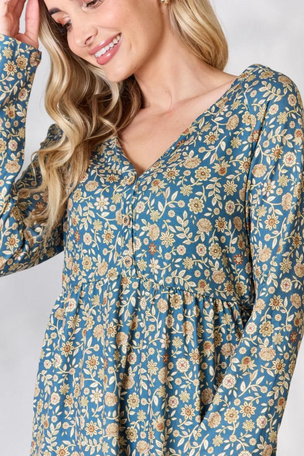 Woman wearing a blue floral dress with long sleeves on a white background