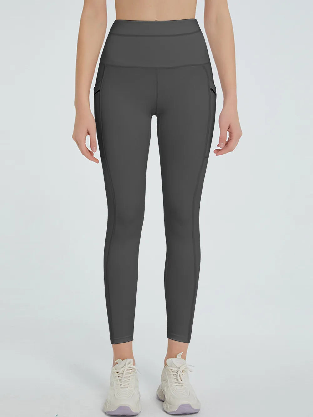 Person wearing dark gray leggings on a light gray background