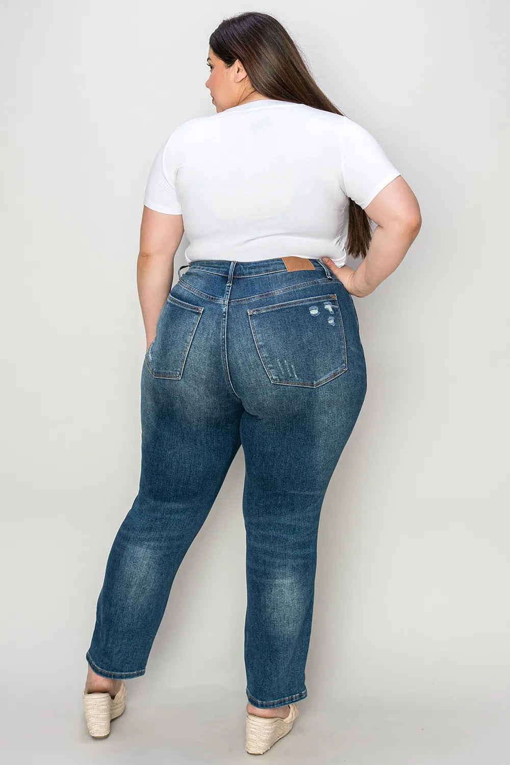 Person wearing blue jeans and a white t-shirt on a plain background