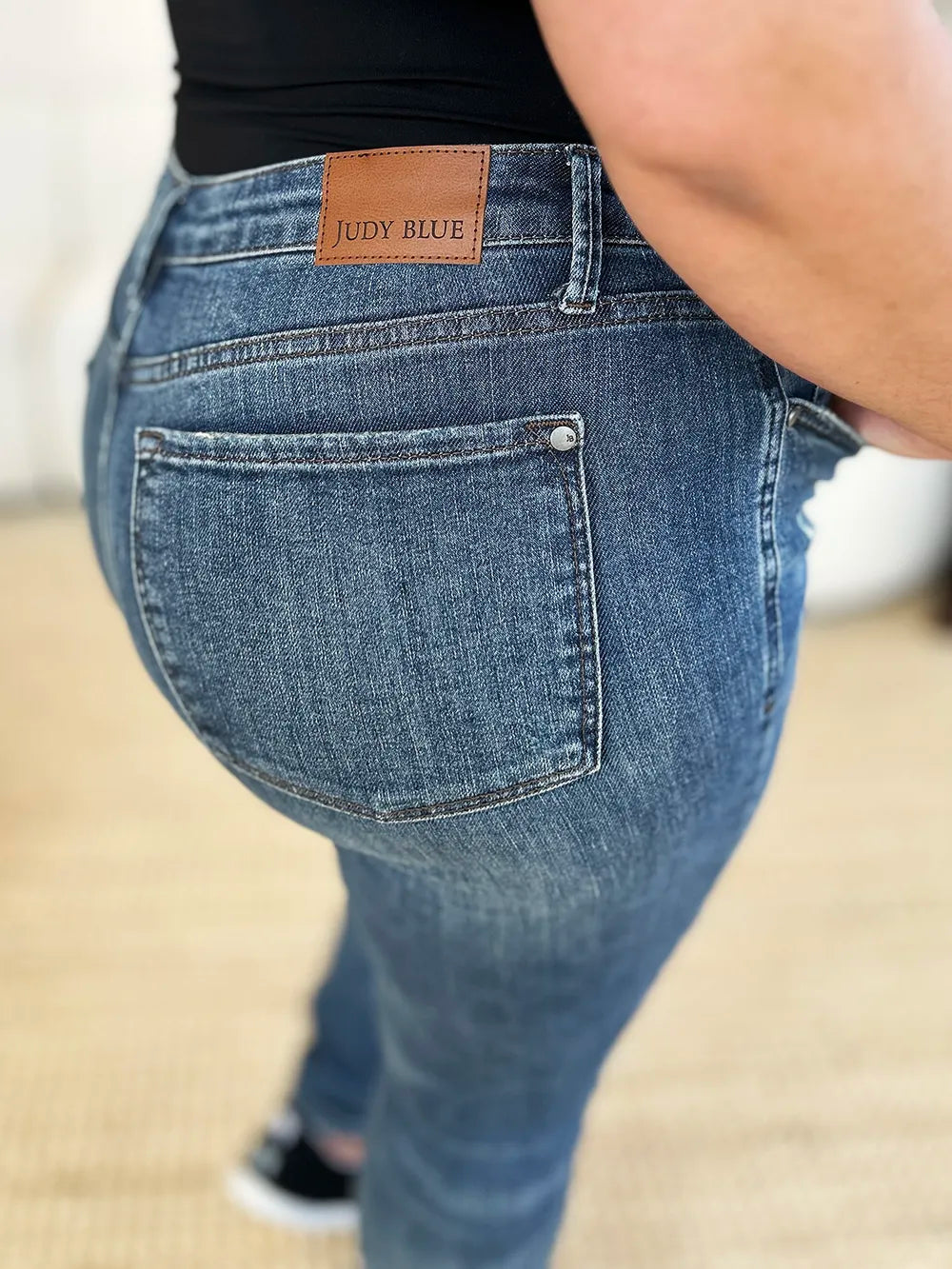 Close-up of blue jeans with a brand label on a neutral background
