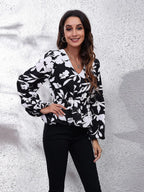Woman wearing a black and white floral blouse against a textured white background