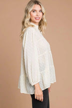 Woman wearing a white blouse with long sleeves against a beige background
