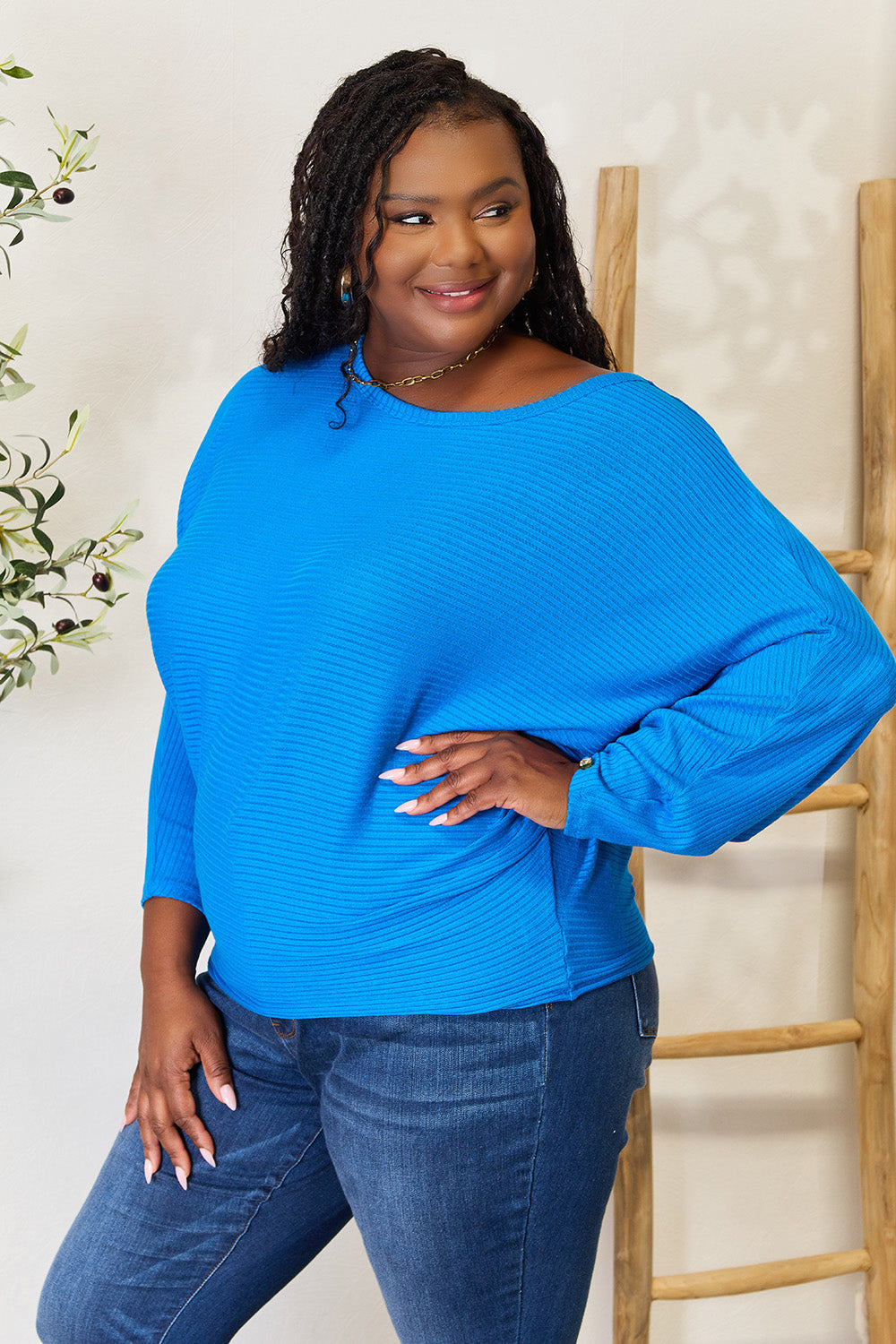 Woman wearing a blue sweater and jeans against a white background