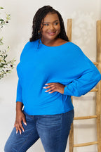 Woman wearing a blue sweater and jeans against a white background