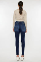 Woman wearing blue jeans and a beige top on a white background