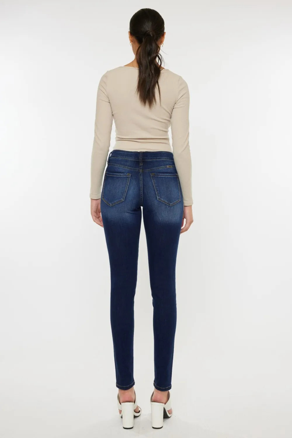 Woman wearing blue jeans and a beige top on a white background