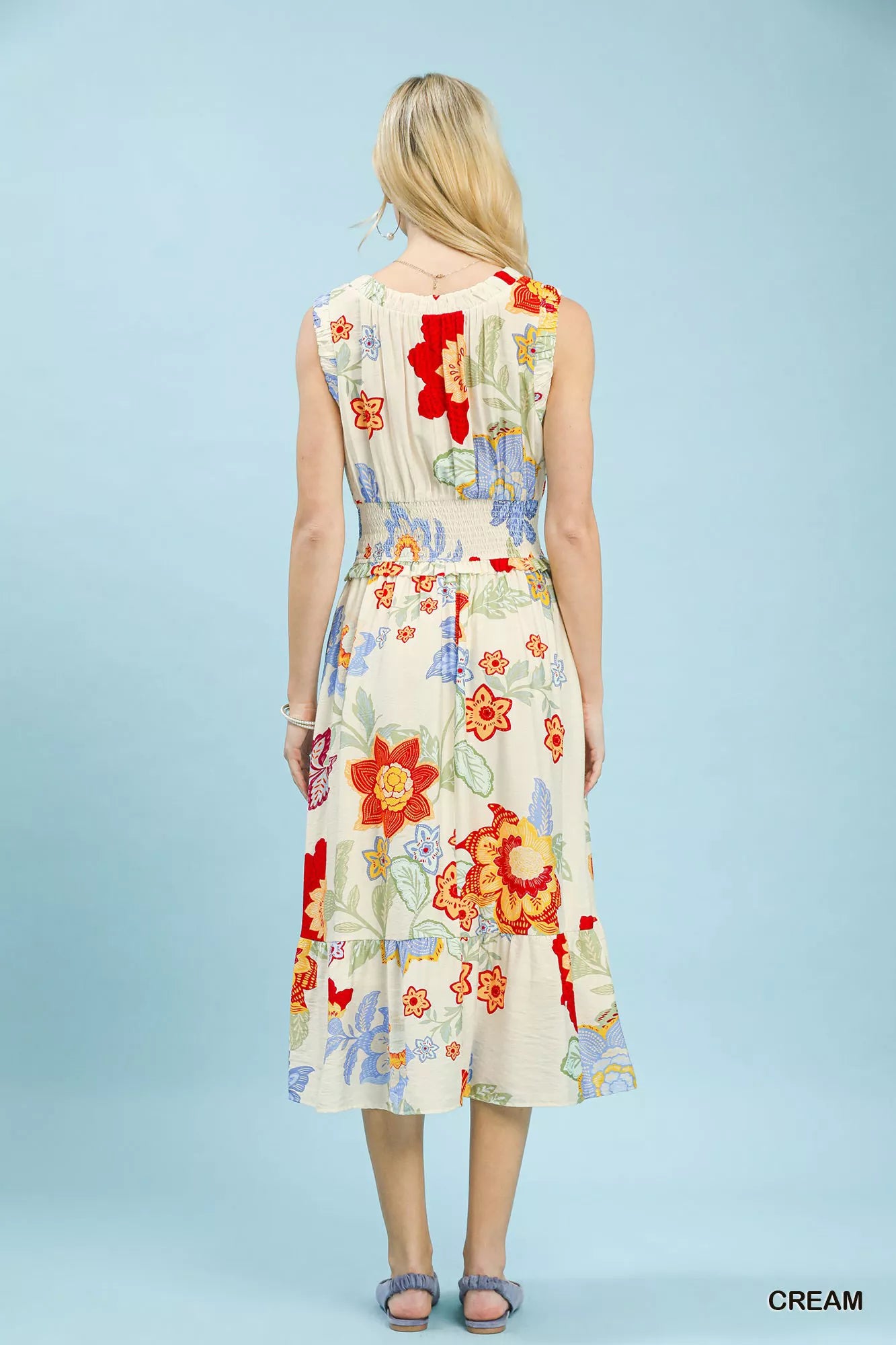 Woman wearing a colorful floral dress against a light blue background