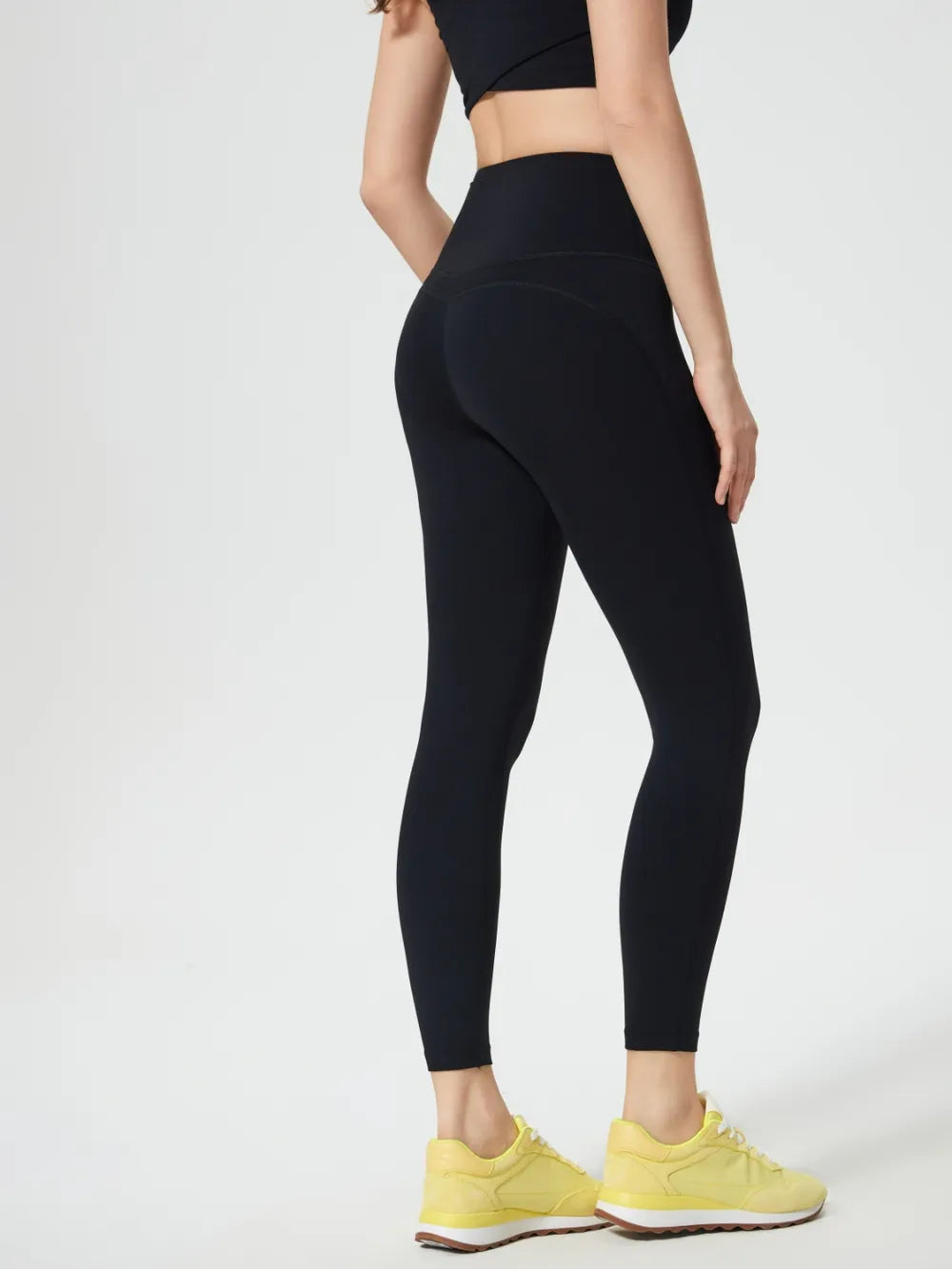 Person wearing black leggings and yellow sneakers on a white background