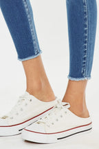 White sneakers with red accents worn with blue jeans on a white background
