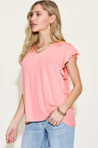 Woman wearing a pink top and blue jeans against a plain background