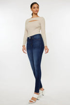 Woman wearing a beige sweater and blue jeans on a white background