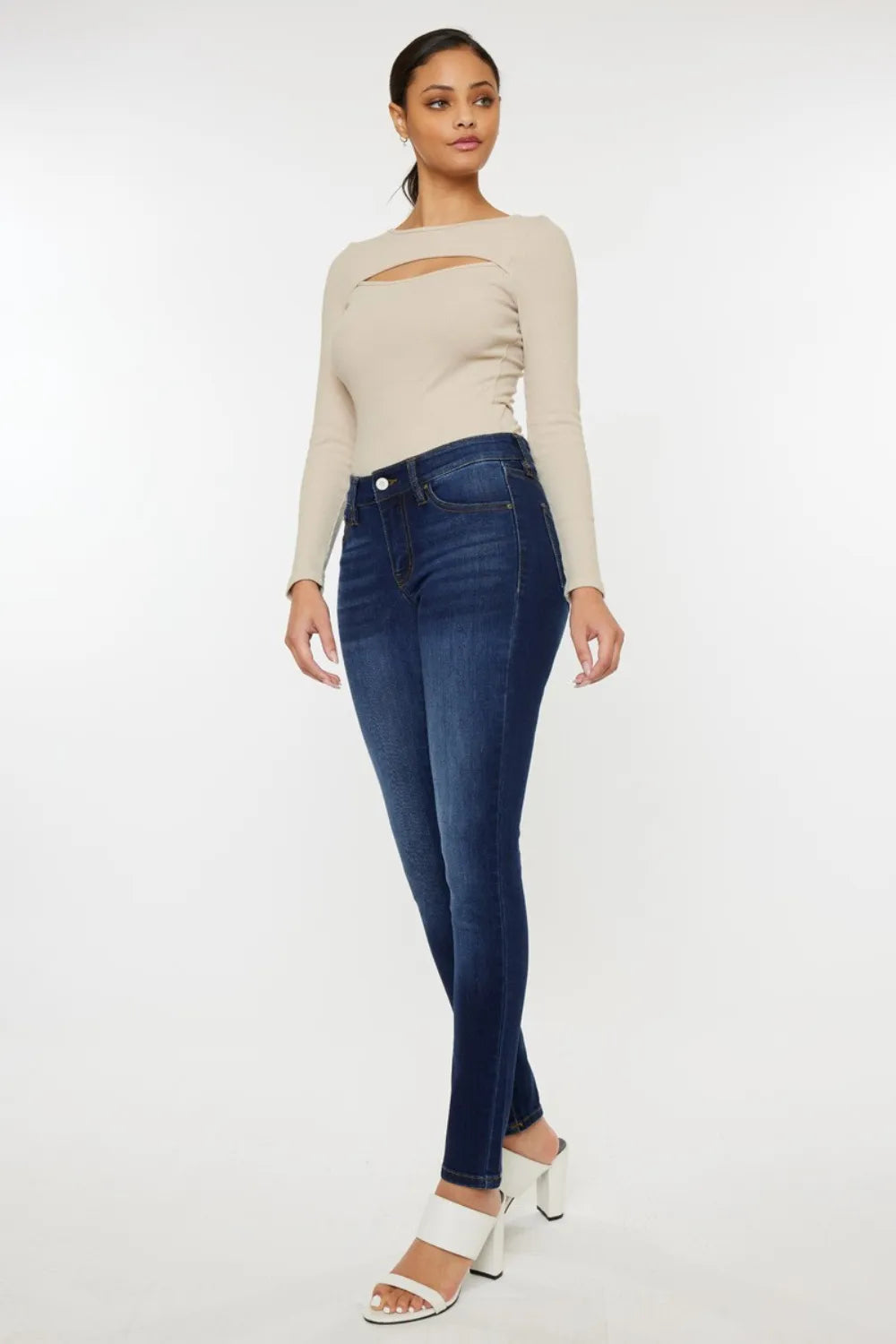 Woman wearing a beige sweater and blue jeans on a white background
