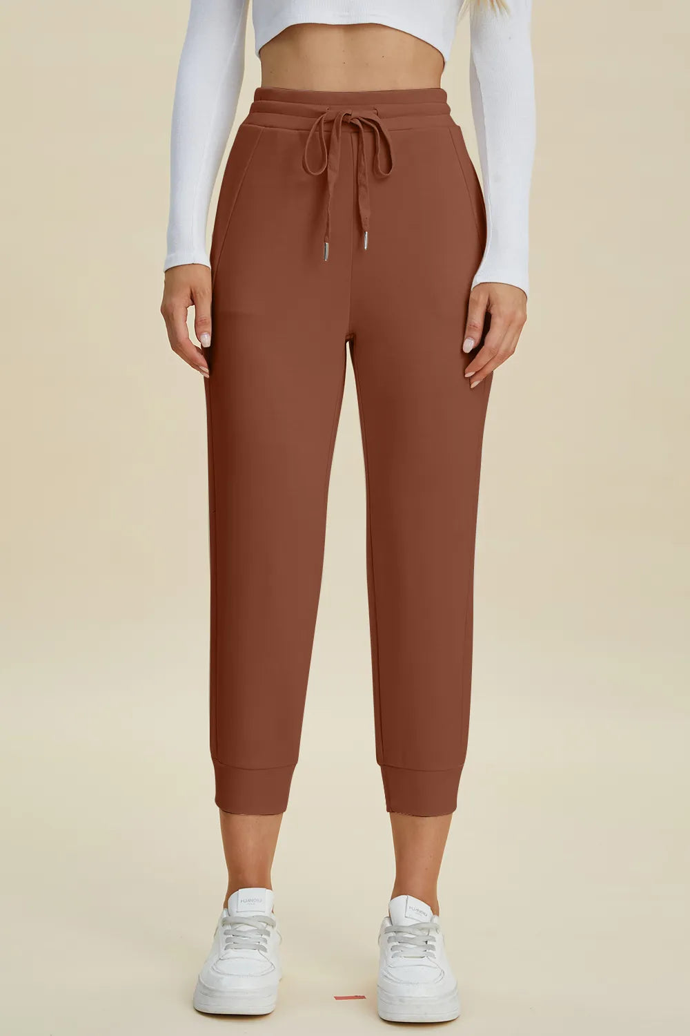 Brown jogger pants worn by a person on a beige background