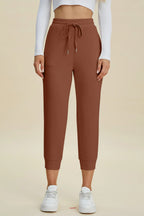 Brown jogger pants worn by a person on a beige background