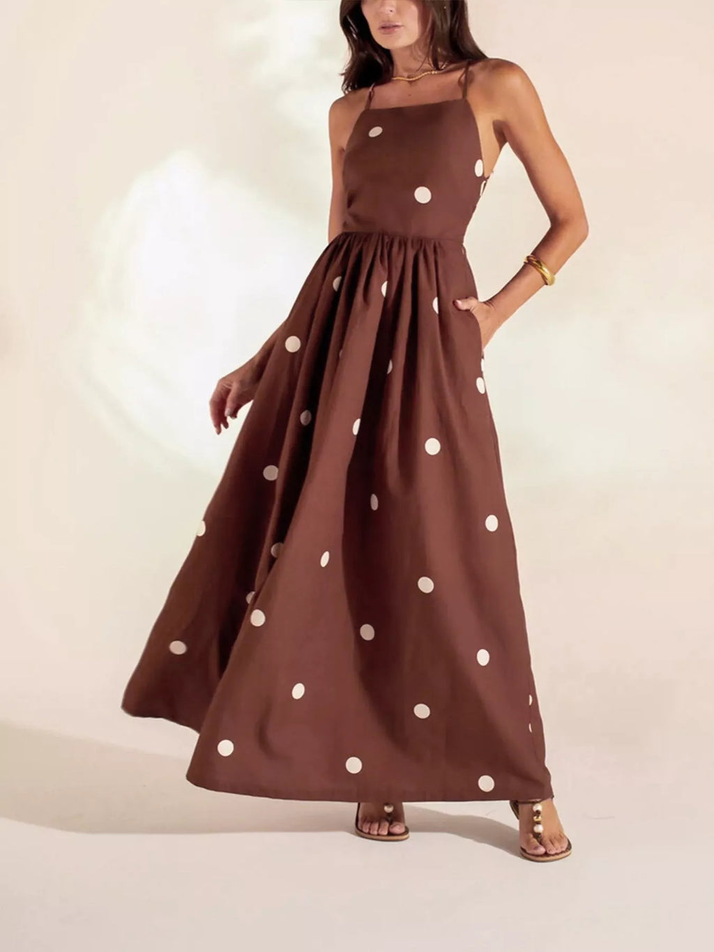 Brown dress with white polka dots worn by a model on a plain background
