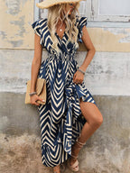 Woman wearing a blue and white patterned dress against a textured wall.