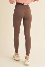 Person wearing brown leggings on a beige background