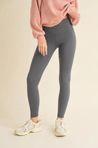 Person wearing gray leggings and a pink sweatshirt on a beige background