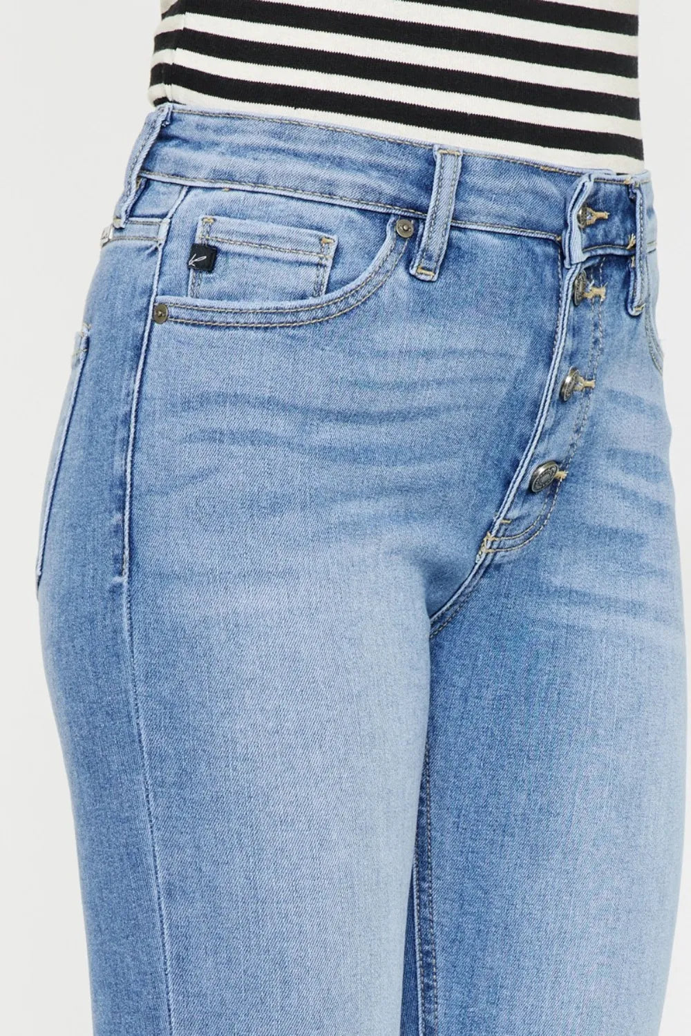 Close-up of light blue jeans with a striped shirt in the background