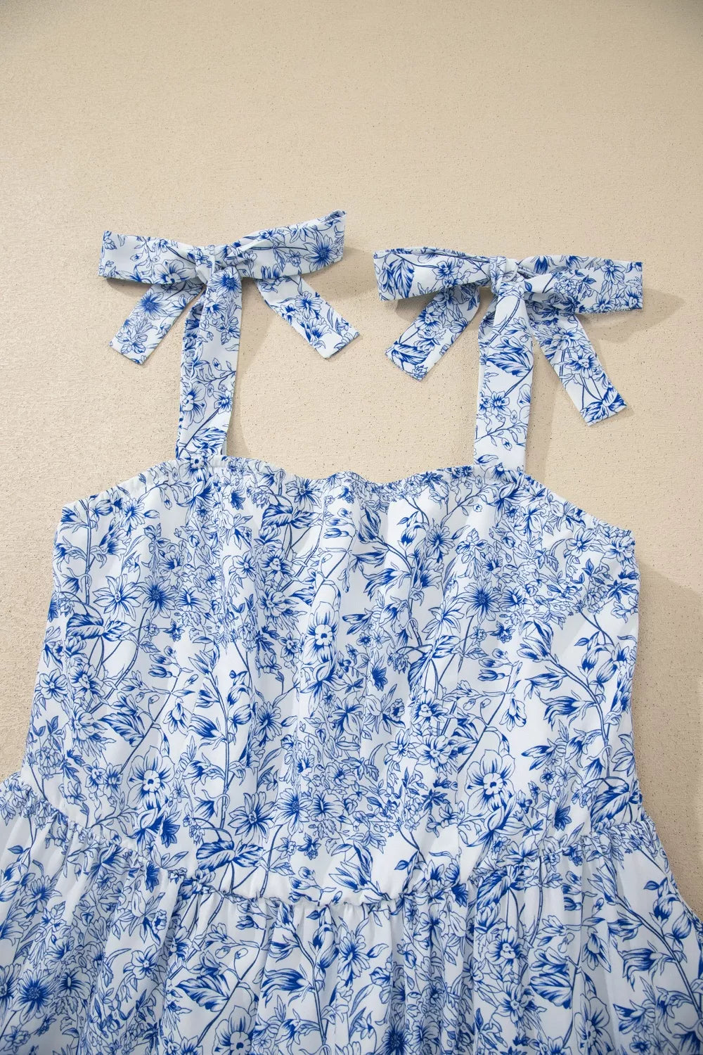 Blue floral dress with bow straps on a beige background