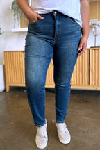 Person wearing blue jeans and white sneakers indoors.