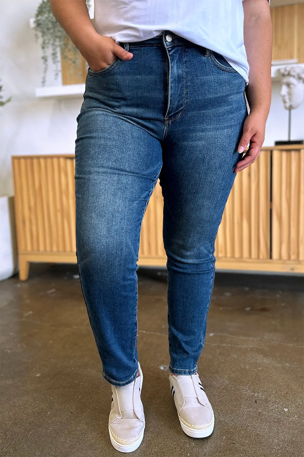 Person wearing blue jeans and white sneakers indoors.
