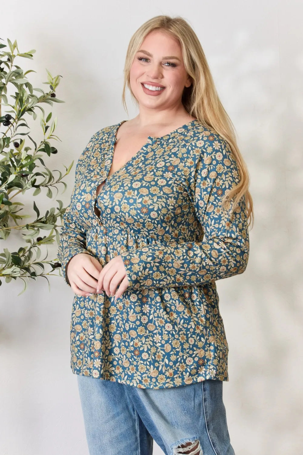 Woman wearing a floral blouse and jeans with a white background