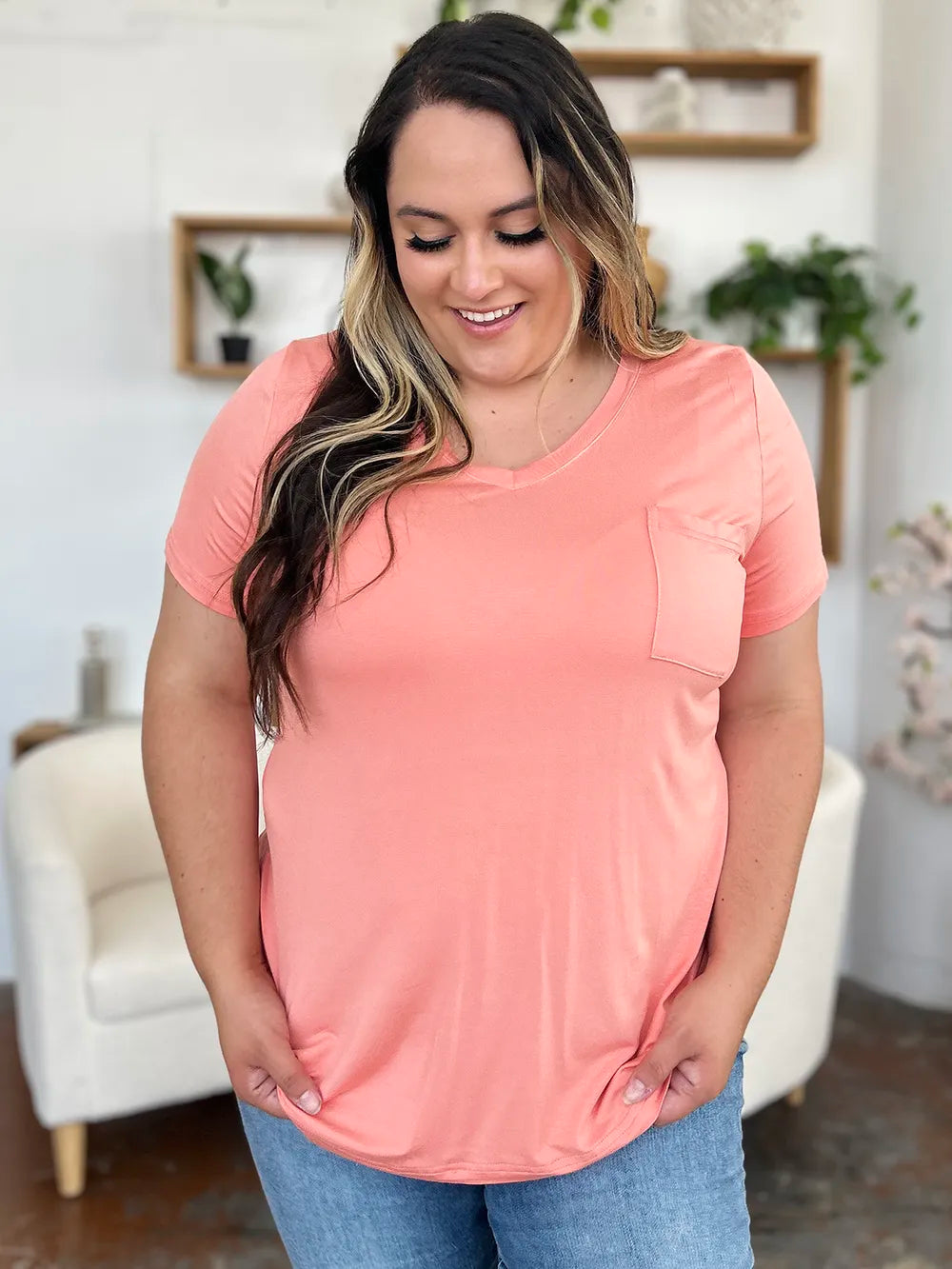 Woman wearing a pink t-shirt with a pocket in a home setting
