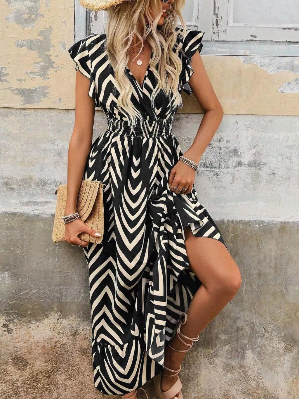 Woman wearing a black and white zebra print dress against a rustic wall.