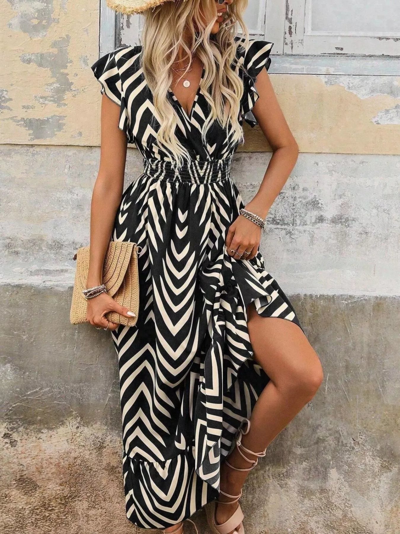 Woman wearing a black and white zebra print dress against a rustic wall.