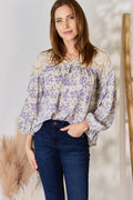 Woman wearing a floral blouse and jeans against a neutral background