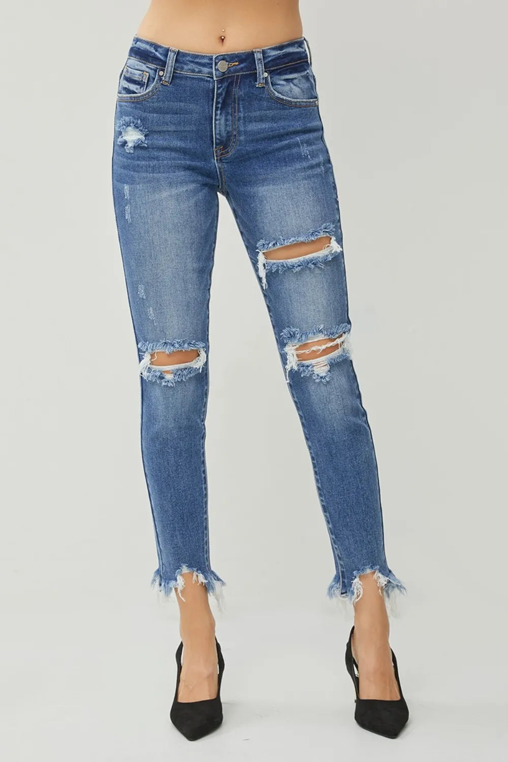Distressed blue jeans worn by a person on a white background