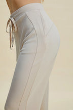 Light gray pants with drawstring waist on a beige background