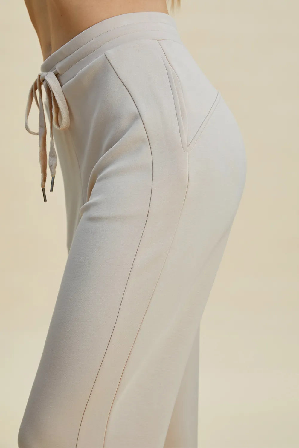 Light gray pants with drawstring waist on a beige background