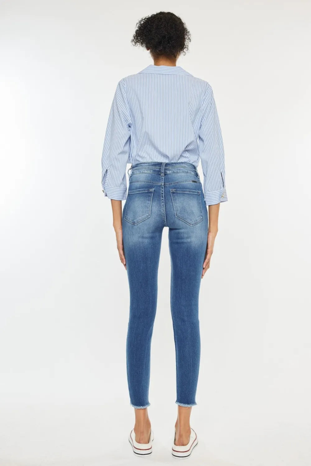 Person wearing a light blue striped shirt and dark blue jeans on a white background