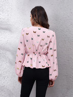 Woman wearing a pink blouse with butterfly pattern against a gray wall