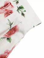 Floral patterned fabric with pink roses and green leaves on a white background