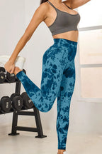 Person wearing blue tie-dye leggings and gray sports bra in a gym setting