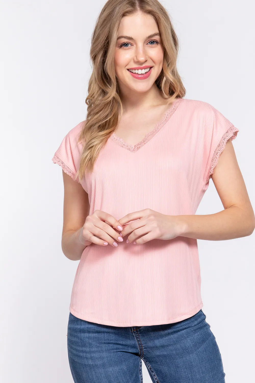 Woman wearing a pink top and blue jeans on a white background
